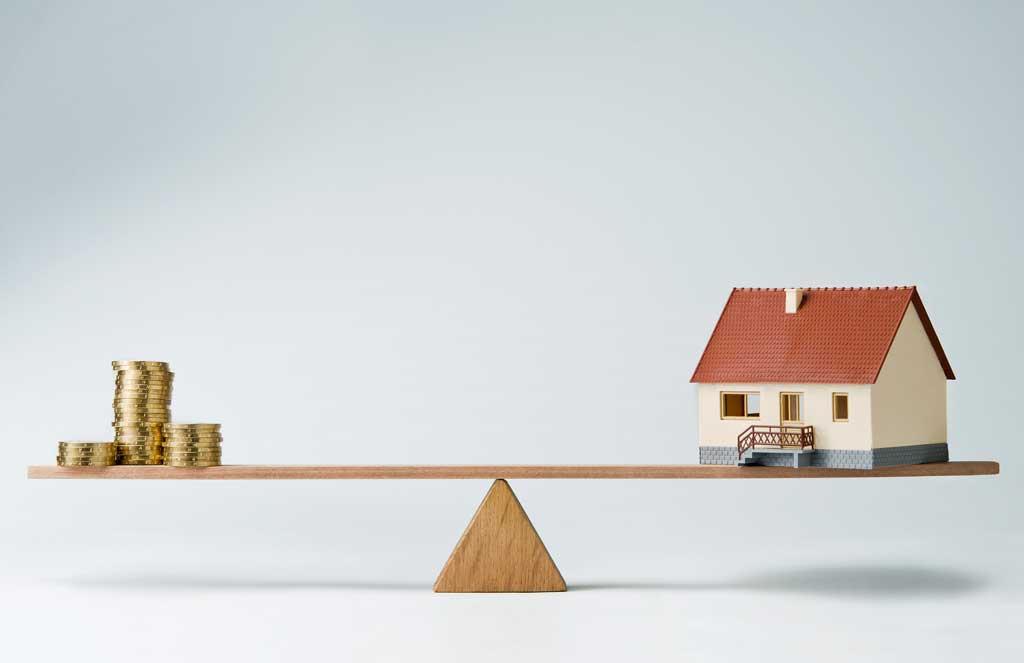 Image of a seesaw with money and a house on each end